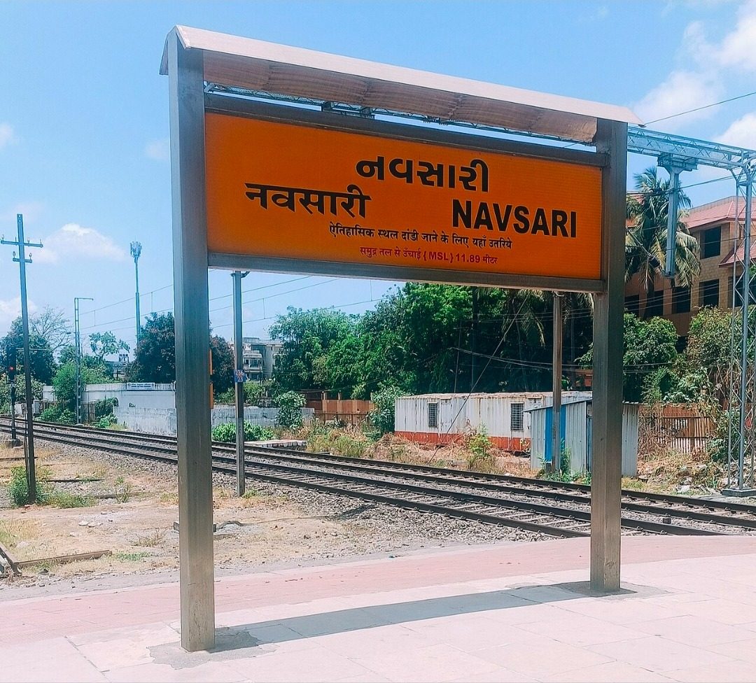 નવસારી રેલવે સ્ટેશનનું નારંગી રંગનું નવસારી – NAVSARI સાઇનબોર્ડ